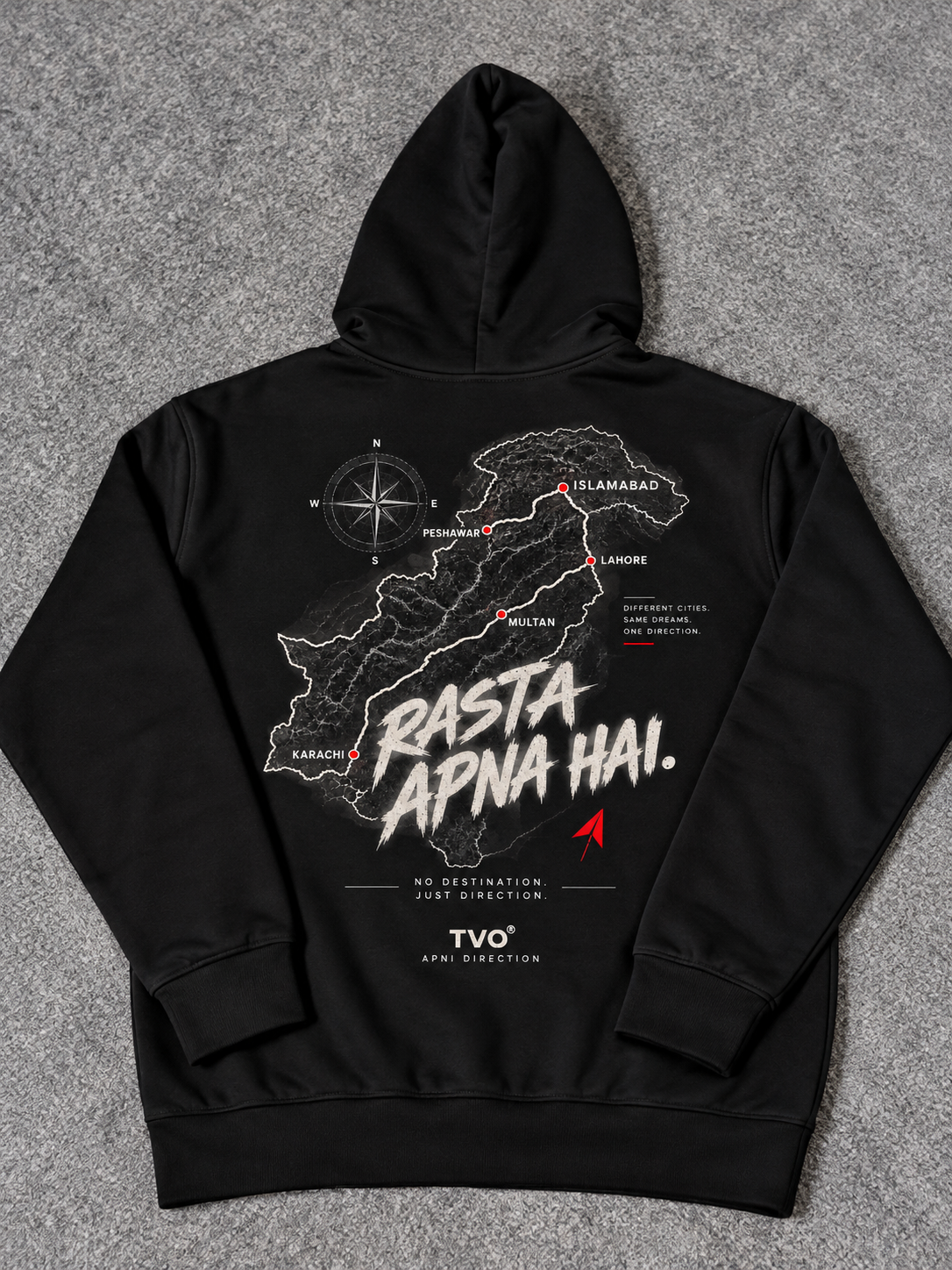 A black pullover hoodie laid flat on a gray textured surface, showing the back side with a large graphic print. The print features a white map outline, a compass rose, and the text 'Rasta Apna Hai.