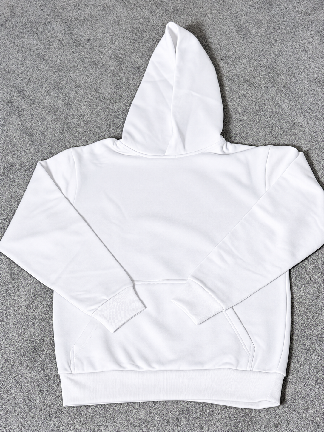 A plain white pullover hoodie laid flat on a textured gray background.
