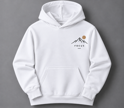 A white pullover hoodie with a small chest graphic featuring a black mountain outline, a tan sun, and the word 'FOCUS' printed below, shown against a dark gray background.