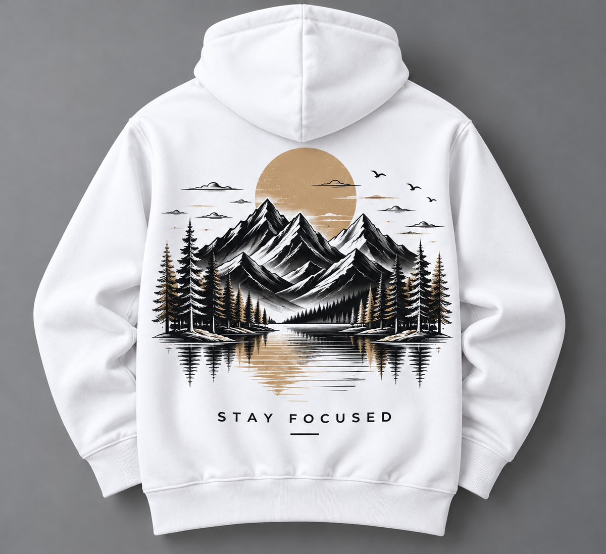 White pullover hoodie shown from the back, featuring a large graphic print of a mountain landscape with pine trees, a reflective lake, birds, and a large tan sun. The text 'STAY FOCUSED' appears below the graphic.