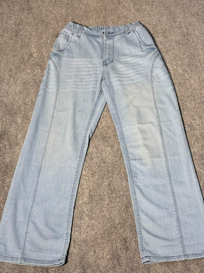 Light wash blue denim jeans laid flat on a textured gray carpet.