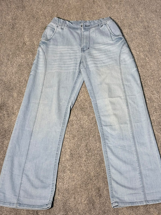 Light wash blue denim jeans laid flat on a textured gray carpet.
