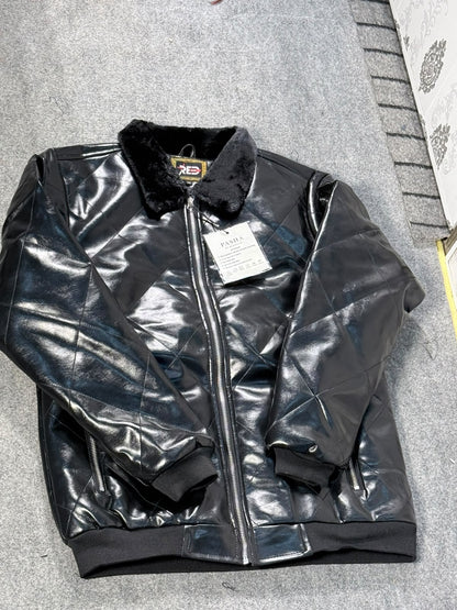 A black faux-leather bomber jacket with a fuzzy black collar and a front zipper, laid flat on a gray textured surface. A white retail tag is attached to the zipper.