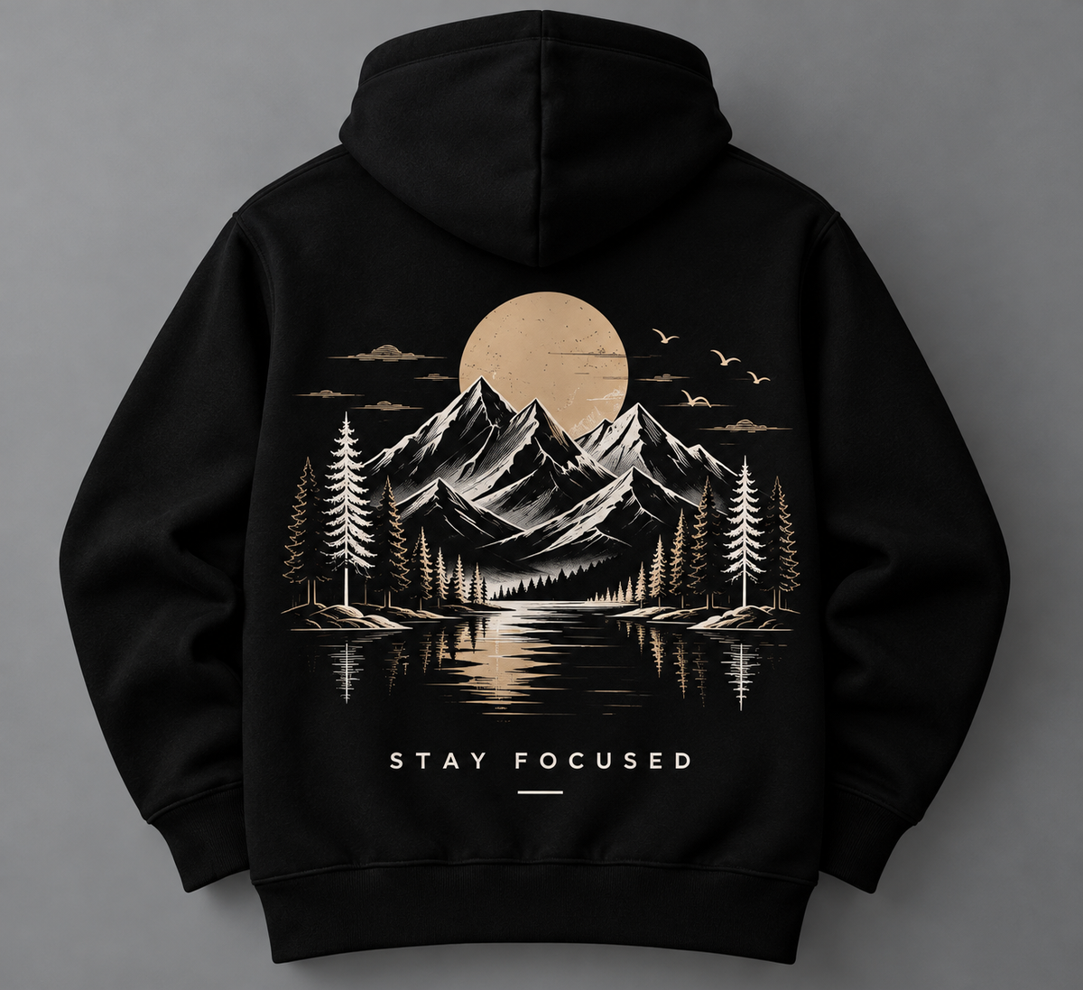 A black pullover hoodie shown from the back, featuring a large graphic print of a mountain landscape with a lake, pine trees, birds, and a large sun or moon. The text 'STAY FOCUSED' is printed below the graphic in white.