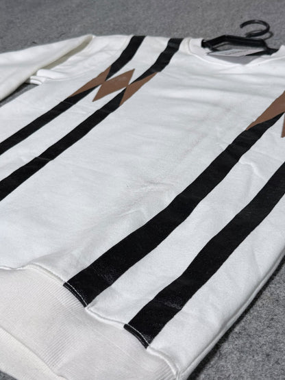 A white crewneck sweatshirt featuring bold black vertical stripes and brown lightning-bolt graphics on the chest, laid flat on a gray textured surface.